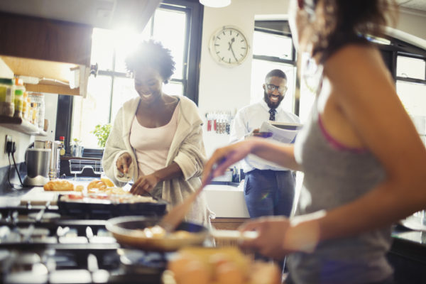 Friend roommates cooking breakfast in kitchen